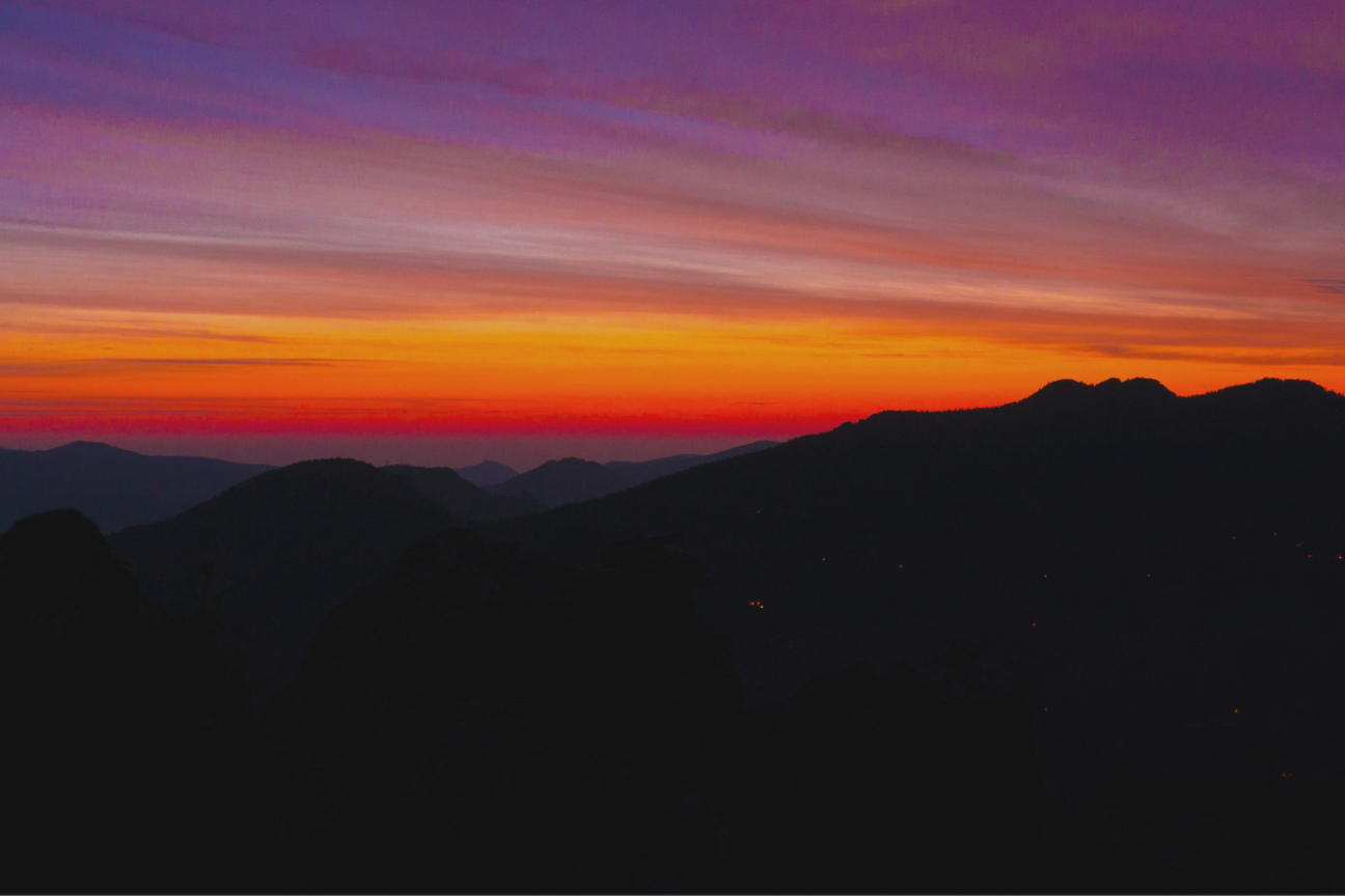 sunset over a silhouette of a mountain range